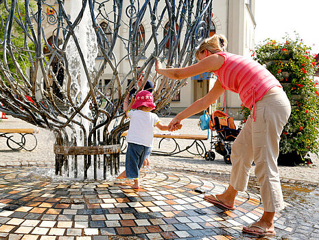 Mutter mit Kind in der Warener Innenstadt am Springbrunnen